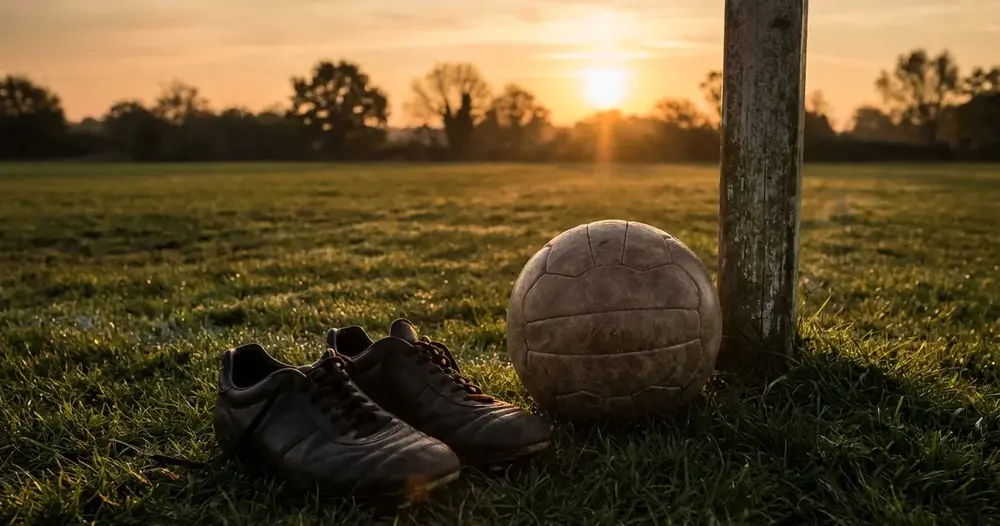 chuteiras e bola na grama ao lado da trave